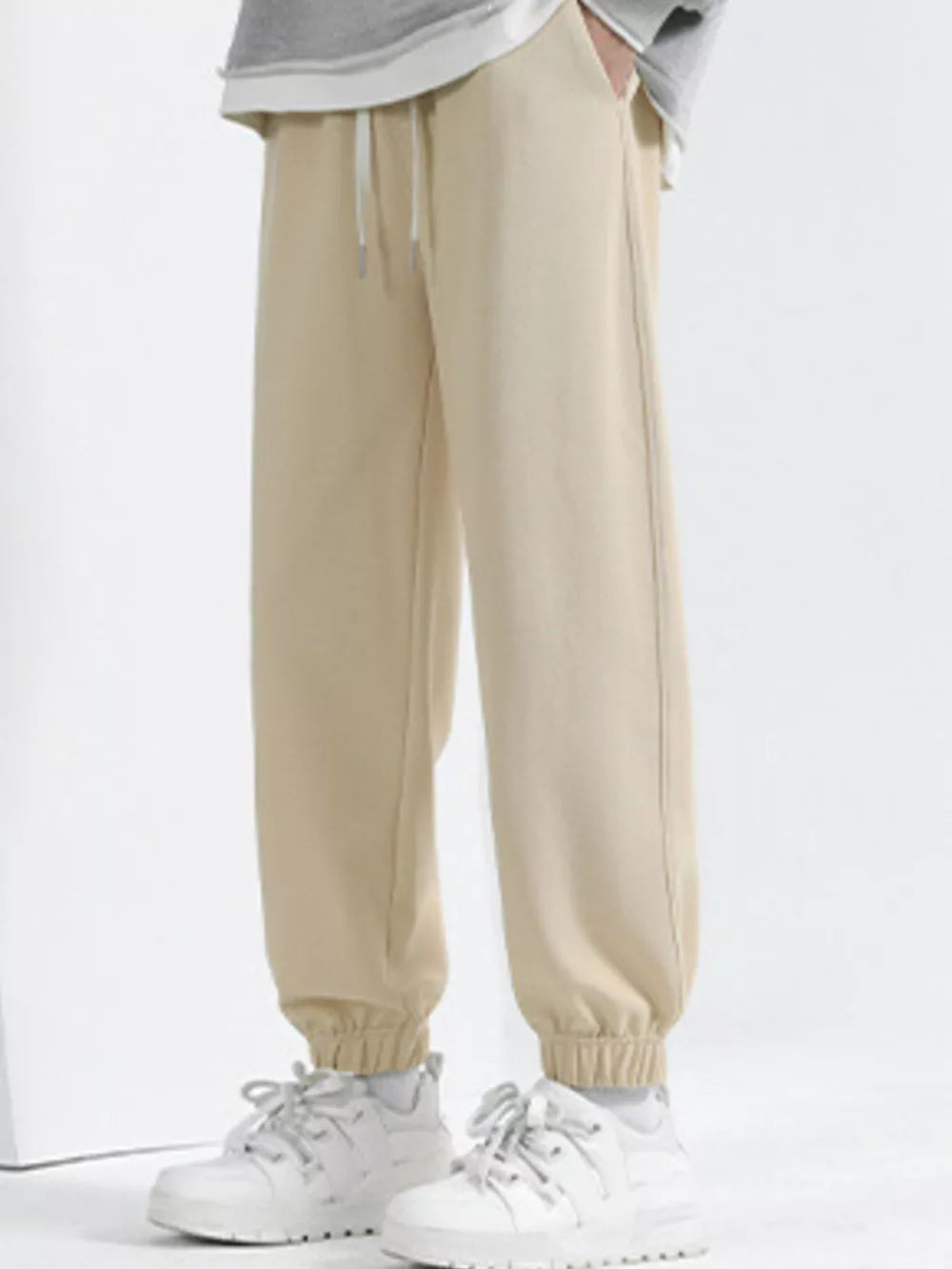 Men's tan loose fit sweatpants with drawstring and cuffed ankles.