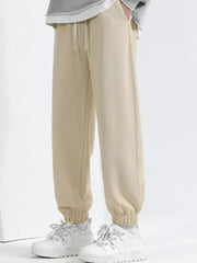 Men's tan loose fit sweatpants with drawstring and cuffed ankles.