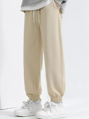 Men's tan loose fit sweatpants with drawstring and cuffed ankles.
