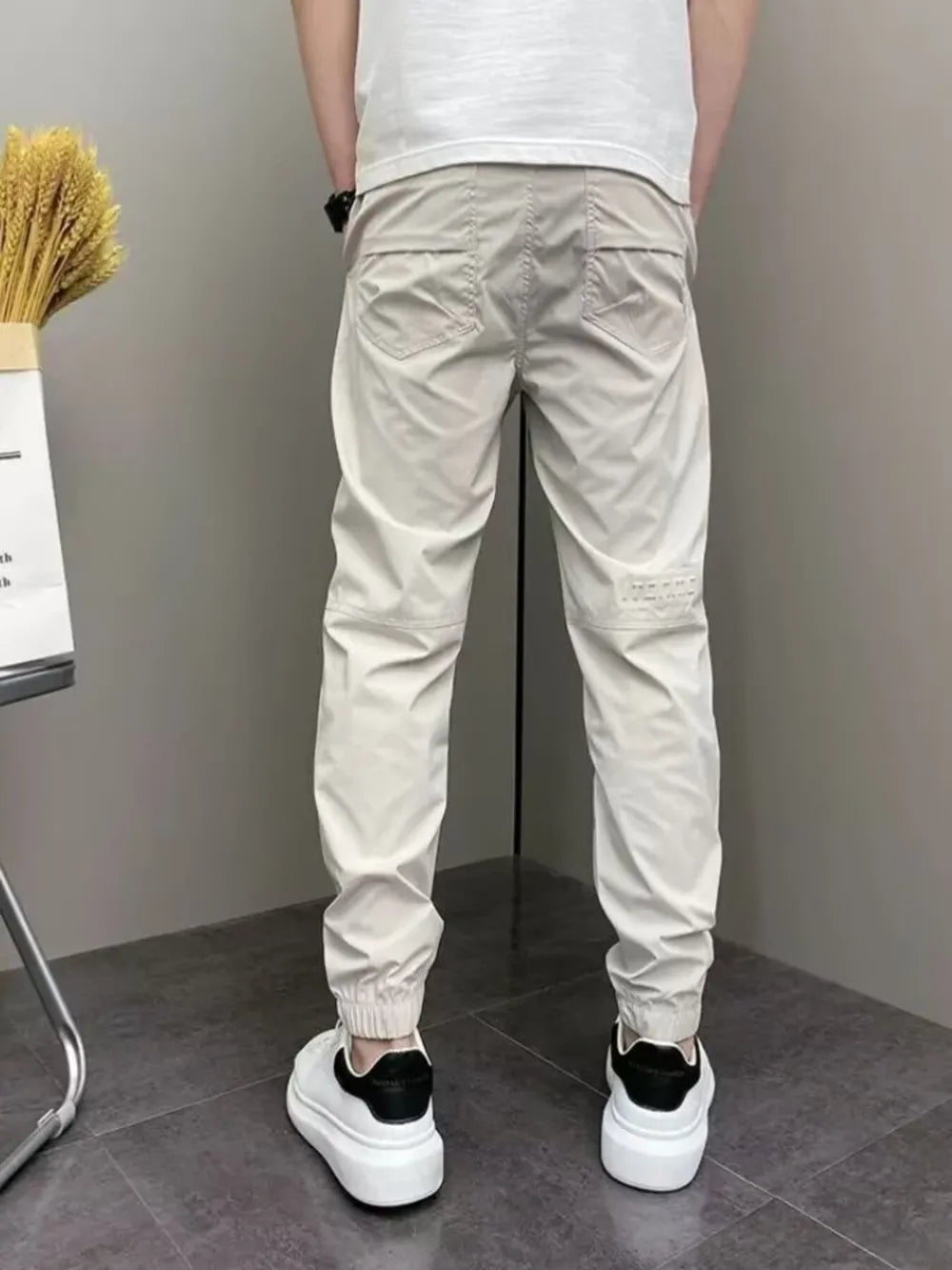 Men's beige cotton sweatpants with drawstring waist and cuffed ankles.