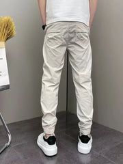 Men's beige cotton sweatpants with drawstring waist and cuffed ankles.