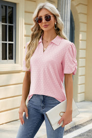 Pink perforated polo top with puff sleeves and V-neck, styled with jeans and a clutch.