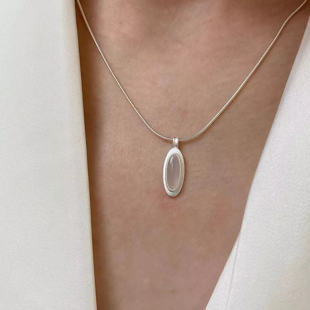 Geometric agate pendant necklace in brushed silver with a white oval stone.