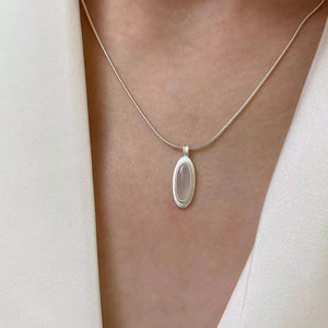 Geometric agate pendant necklace in brushed silver with a white oval stone.