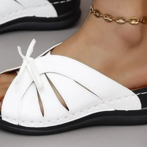 White leather lace-up cutout slides with black sole and ankle bracelet.