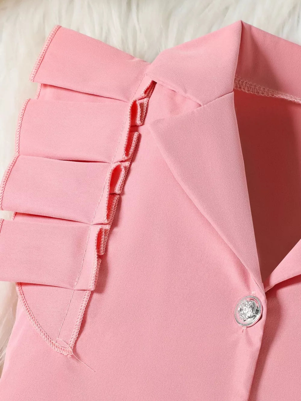 Pink toddler outfit detail with ruffled collar and decorative button