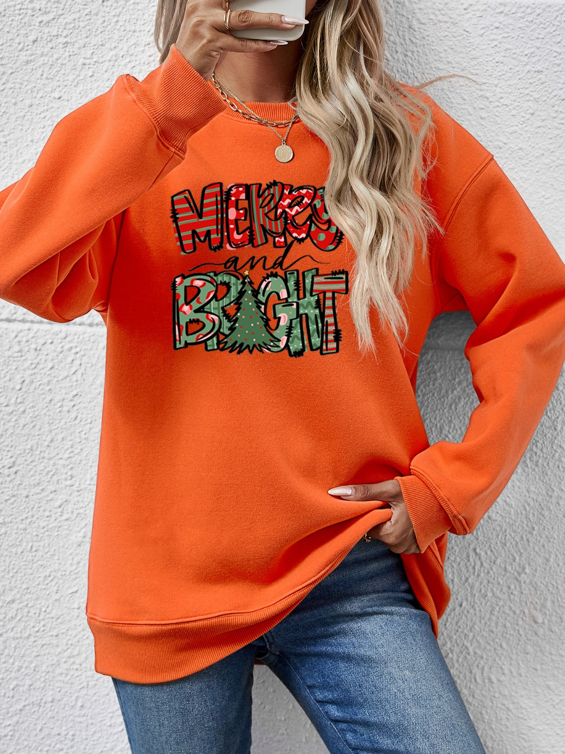 Orange crewneck sweatshirt with Merry and Bright Christmas graphic and tree detail