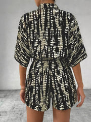 Black and white striped belted romper with collared neckline and short sleeves.