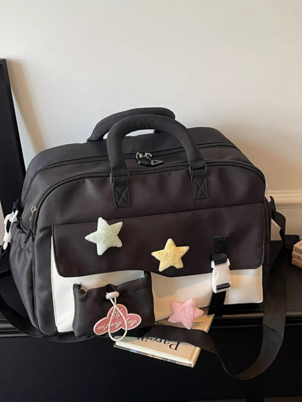 Chic color block travel bag in black and white with star embellishments and a buckle closure.