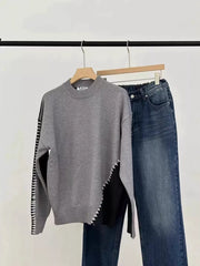 Gray mock neck sweater with black color block detail and contrast stitching, paired with denim jeans.