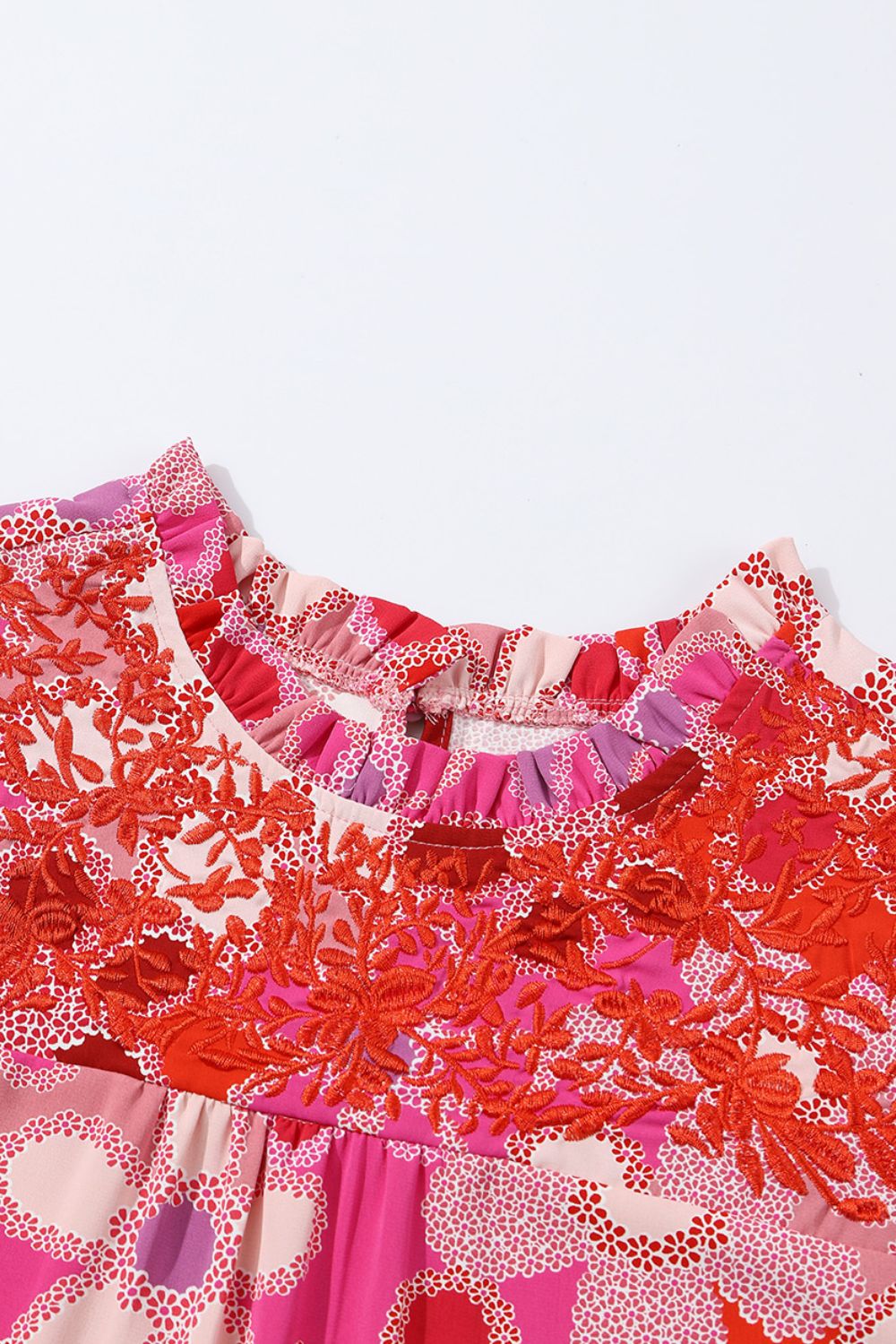 Floral embroidered yoke blouse with ruffle neckline and colorful print.