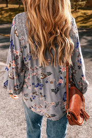 Bohemian floral blouse in dusty blue with lace shoulder detail and tie-front detail.
