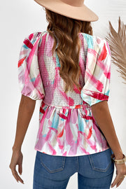 Smocked bodice peplum top with abstract floral print and puff sleeves.