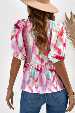 Smocked bodice peplum top with abstract floral print and puff sleeves.