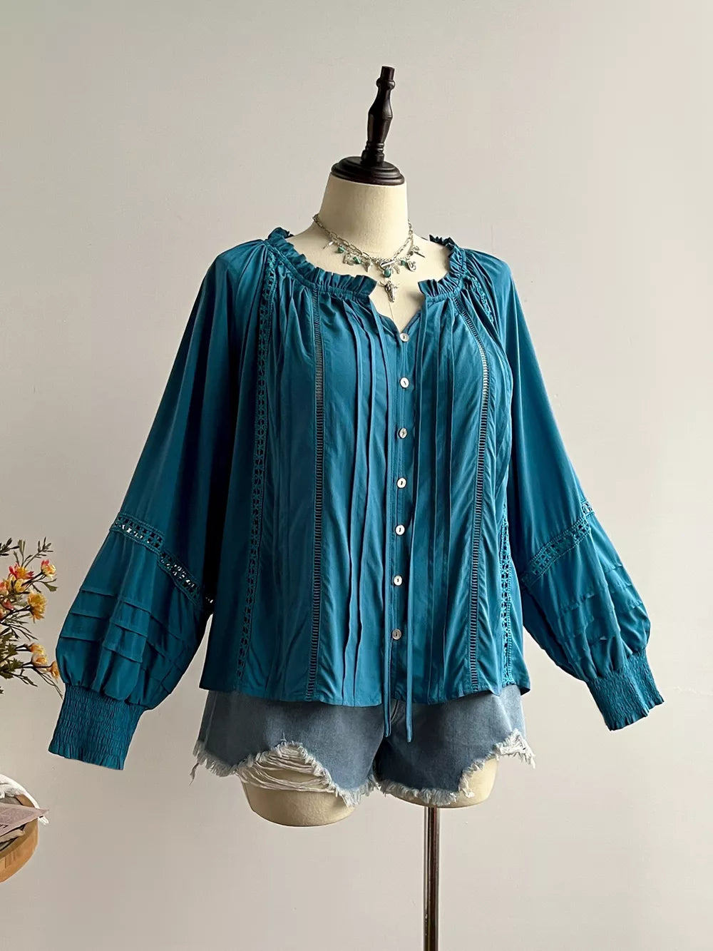Teal ruffled lantern sleeve blouse with button-down front and crochet detail.