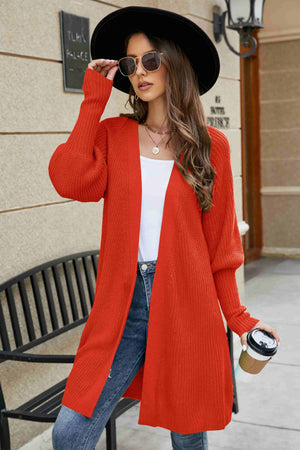 Orange-red knit cardigan with puffed sleeves and a longline cut.