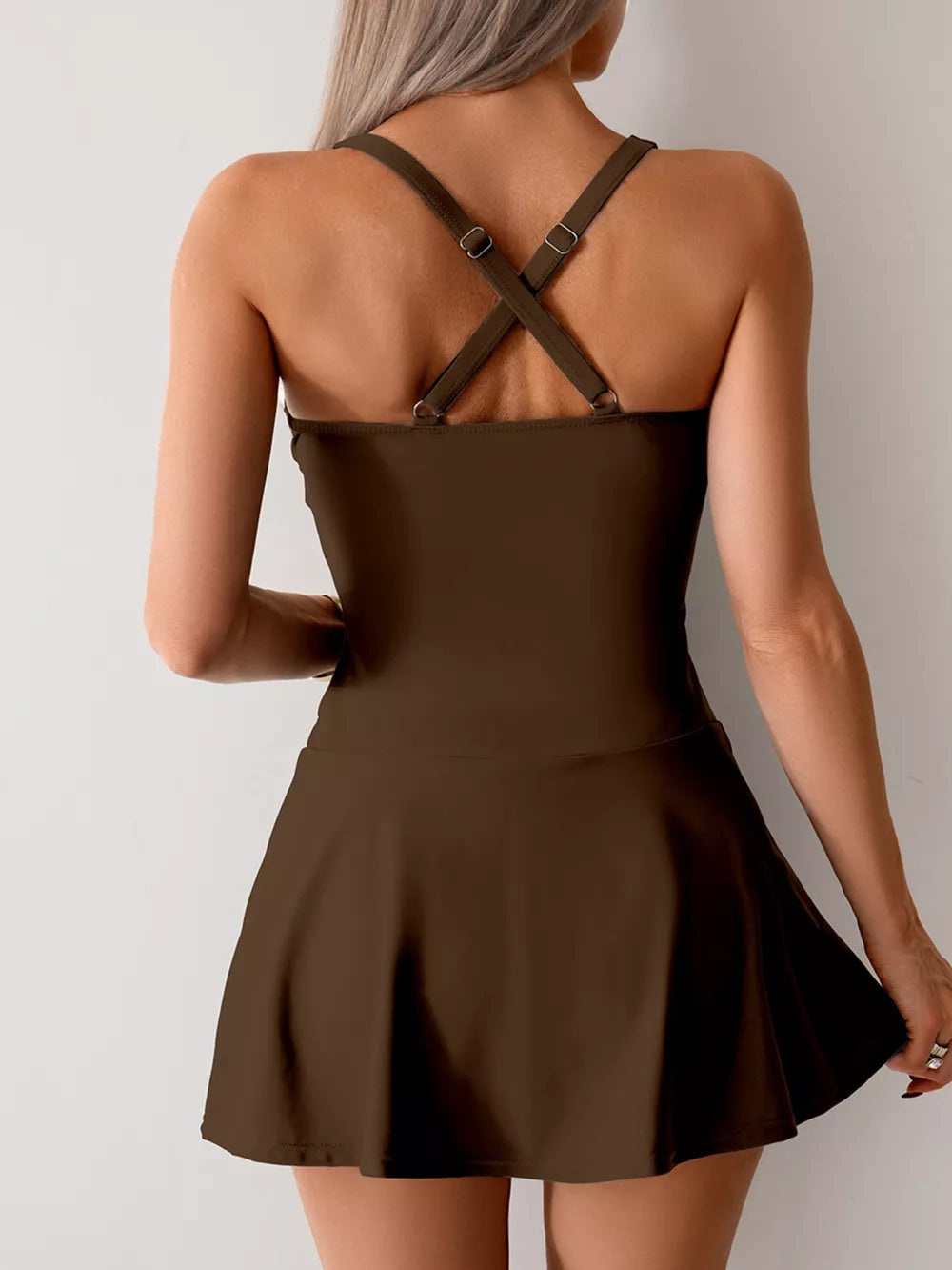 Brown one-piece swimsuit with crisscross straps and a flared skirt.