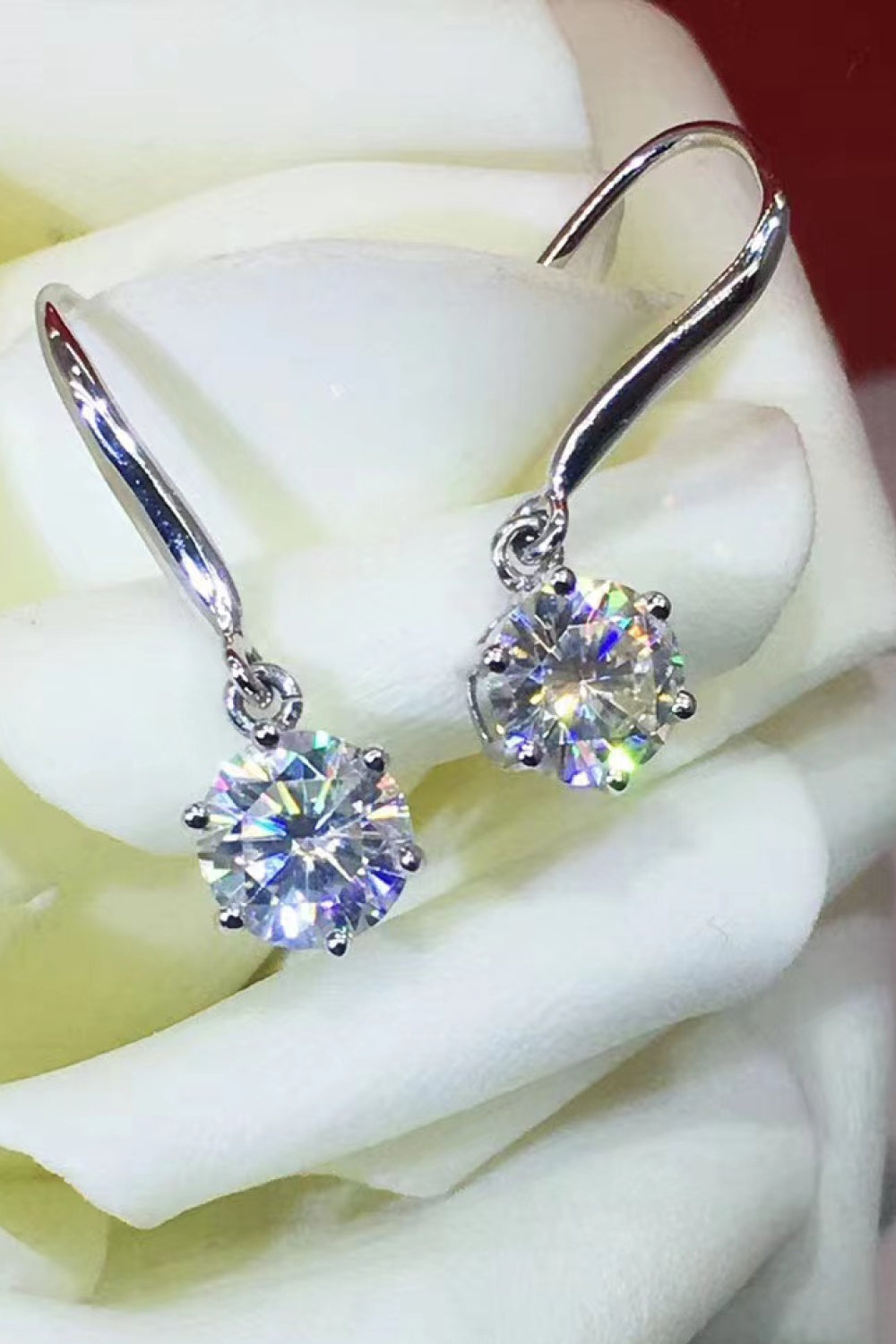 Silver drop earrings with cubic zirconia solitaire stones, reflecting prismatic light.