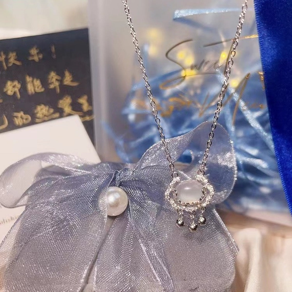 Dainty silver necklace with a chalcedony lock pendant, delicate charms, and crystal accents.