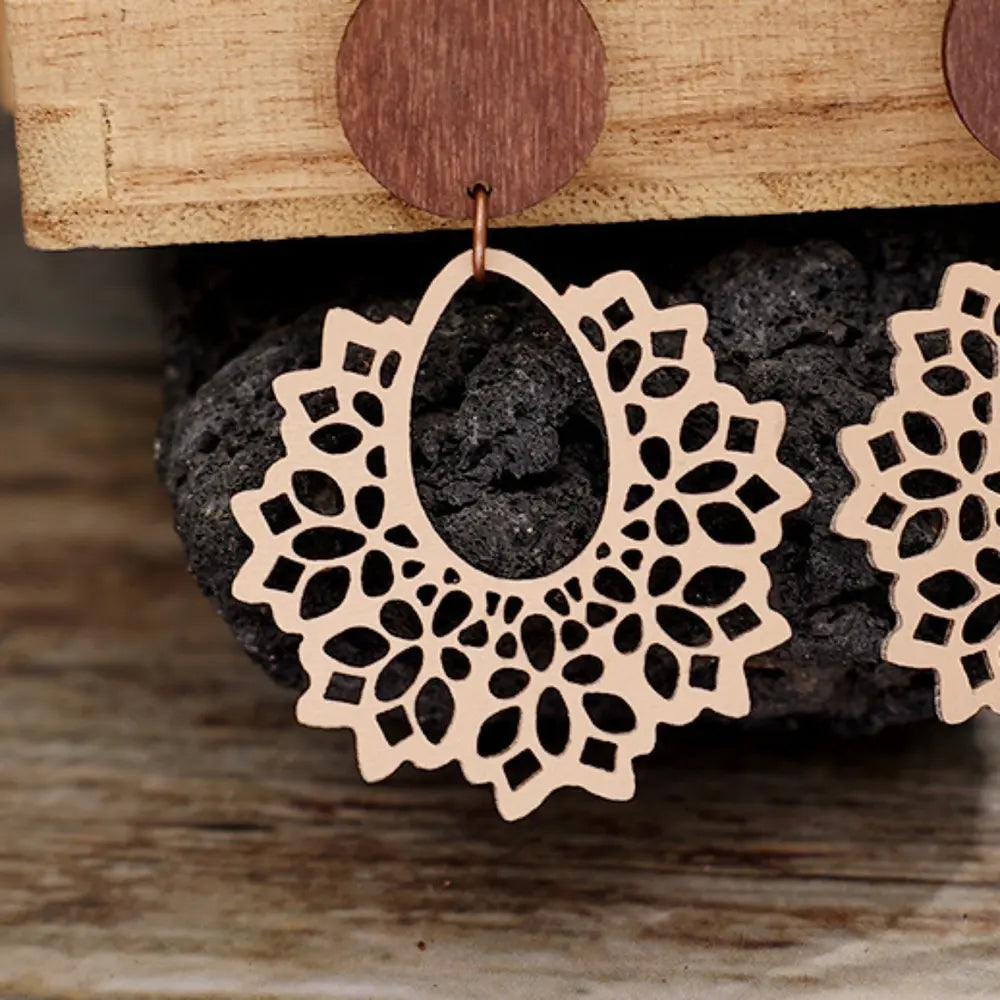 Floral laser-cut wooden drop earrings in tan with intricate cutout pattern.
