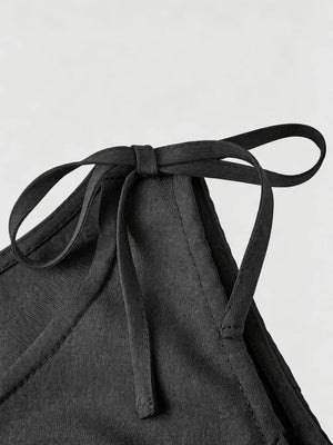 Black embellished vest with tie shoulder straps and textured fabric detail.