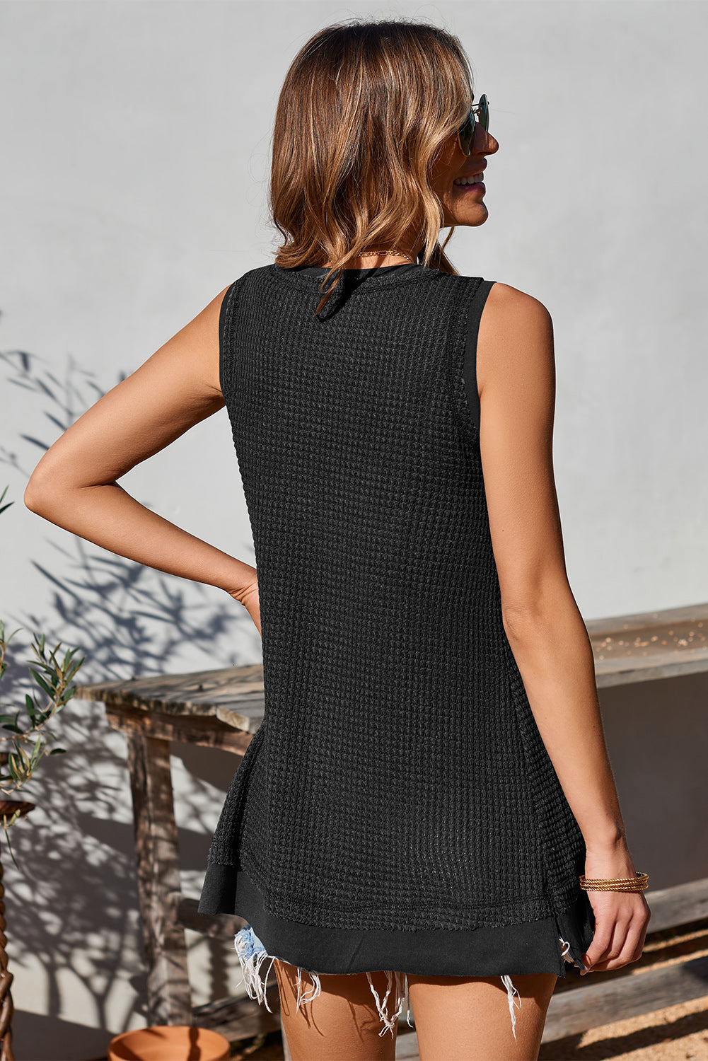 Black waffle knit tank top with asymmetric hem and raw edge detail