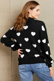Black sweater with white hearts, balloon sleeves, and a mock neck.