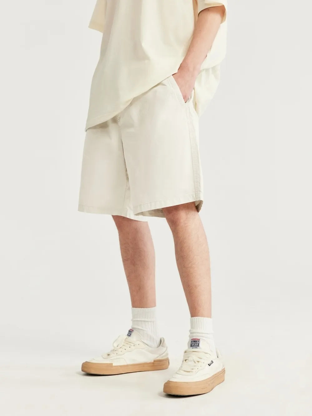 Men's ivory chino shorts with drawstring detail and knee-length cut.