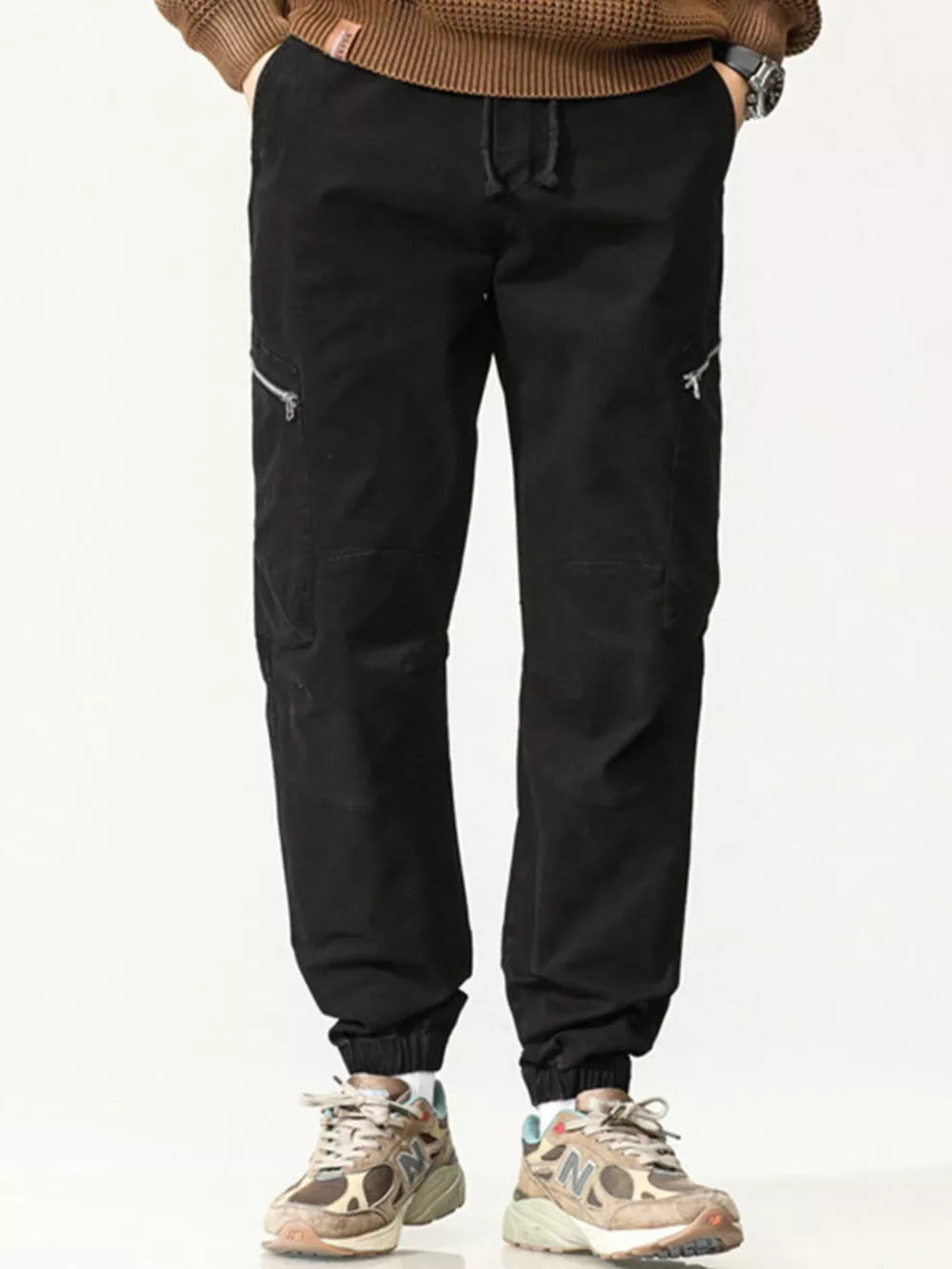 Men's black cotton cargo pants with zippered pockets and drawstring waist.