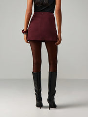 Burgundy high-waisted mini skirt with tie-side detail, styled with black tights and boots.