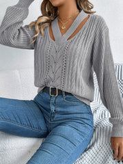 Gray cutout cable knit sweater with V-neck and open knit details.