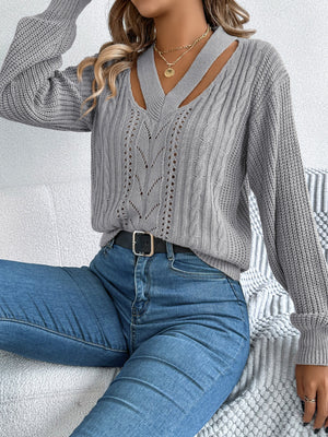 Gray cutout cable knit sweater with V-neck and open knit details.