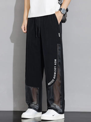 Black sweatpants with mesh panels and wide legs, featuring a drawstring waist and text detail.