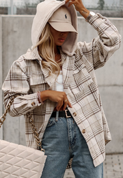 Oversized plaid shacket with attached hoodie and button front, styled with jeans and a baseball cap.