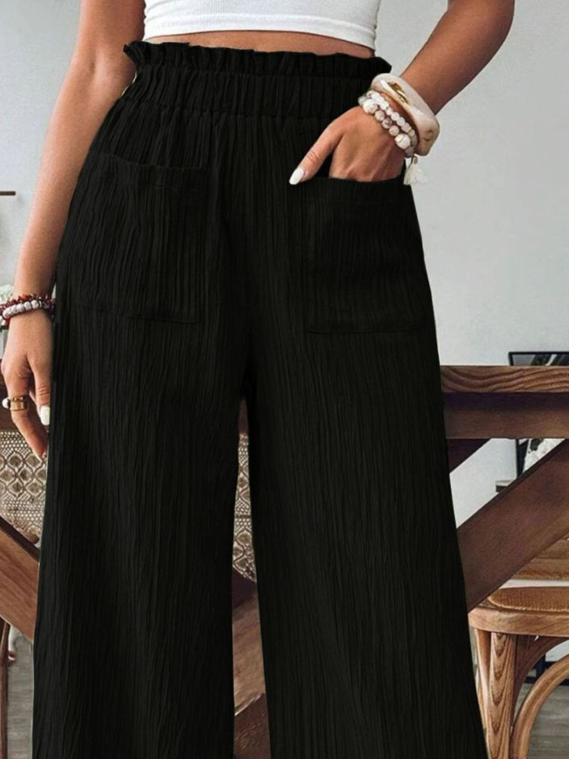 Black textured gauze palazzo trousers with elastic waist and pockets.
