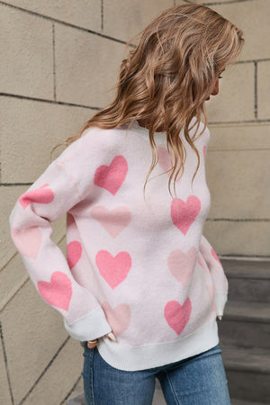 Pink knit crewneck pullover sweater with allover heart motif and white cuffs.