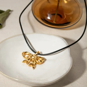 Gold sculptural bow pendant necklace on black wax rope, 18K gold-plated charm