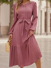 Pink pleated midi dress with long sleeves, tie waist, and tiered hem.