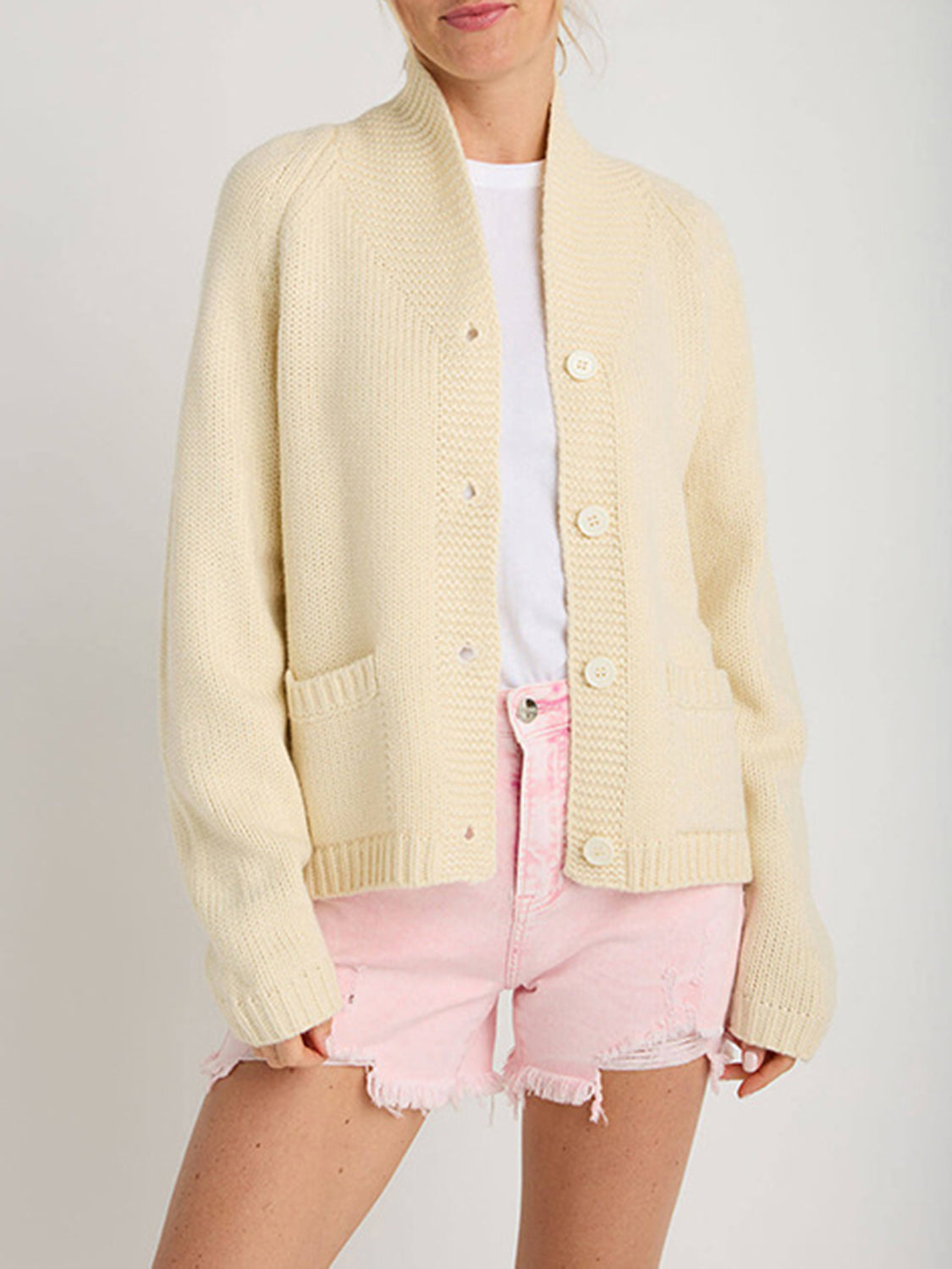 Cream knit buttoned cardigan with pockets and a shawl collar.