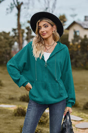 Turquoise textured cable knit zip-up hoodie with drawstring hood and front pocket.