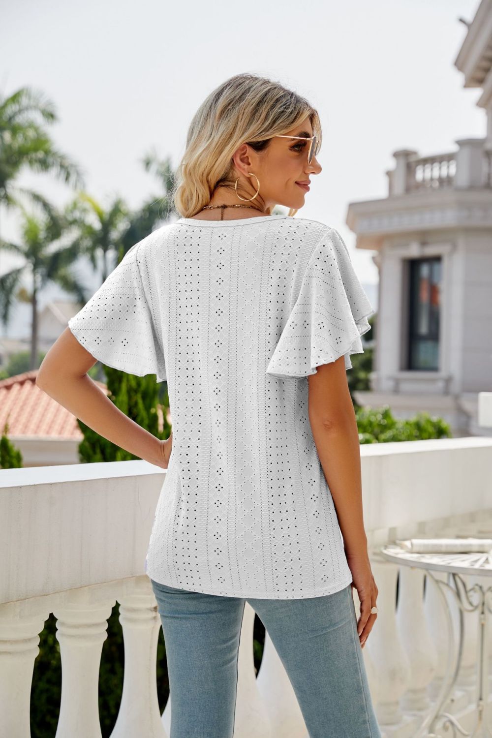 White eyelet flounce sleeve crew neck blouse with intricate patterns.