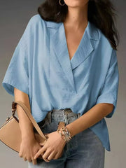 Light blue V-neck half sleeve shirt with a relaxed fit, styled with jeans and a handbag.
