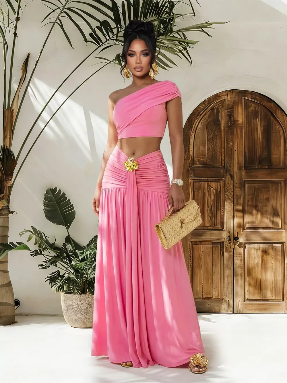 Pink one-shoulder ruched crop top and maxi skirt set with a gold flower detail.