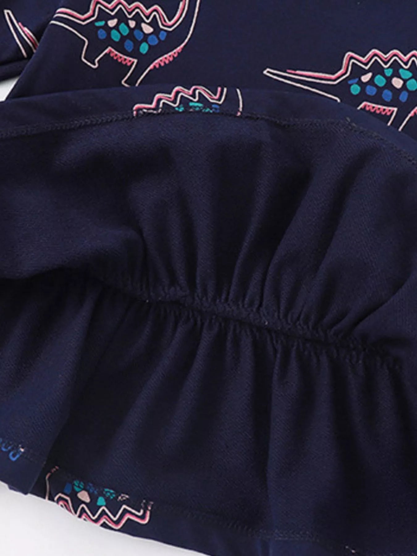 Dark navy cotton sweatshirt with dinosaur print and ruffled hem detail.