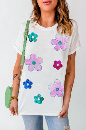 White t-shirt with scattered sequin floral appliqués in pink, blue, and teal.