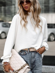 White textured puff sleeve blouse with smocked neck and ruffled cuffs.