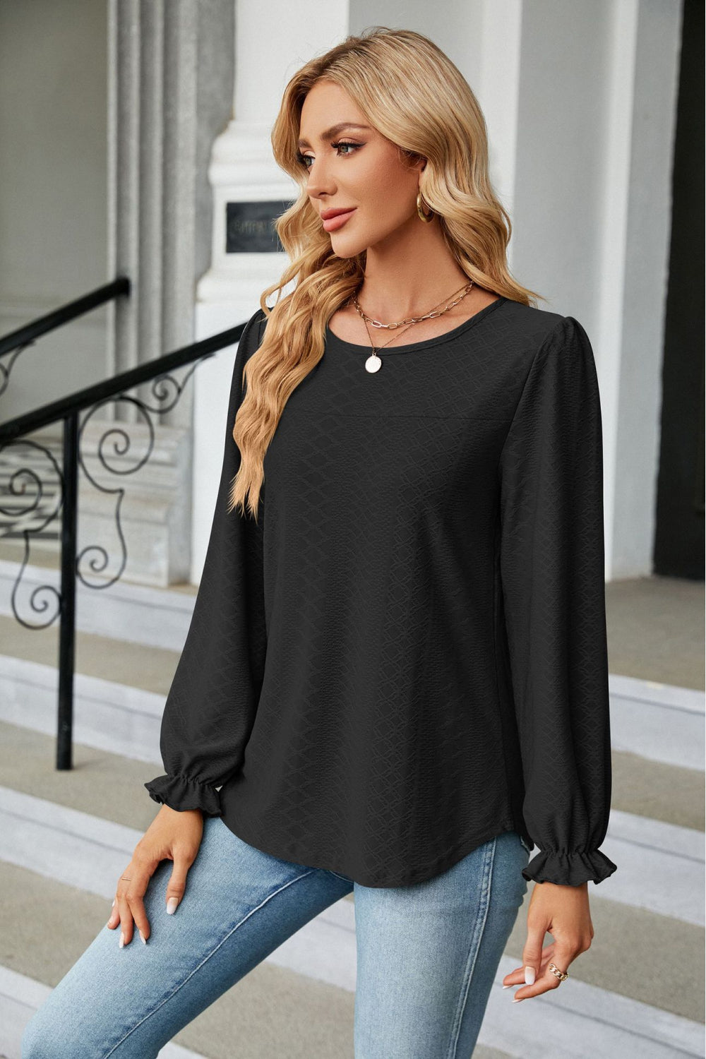 Black textured puff sleeve blouse with ruffle cuffs and round neckline.