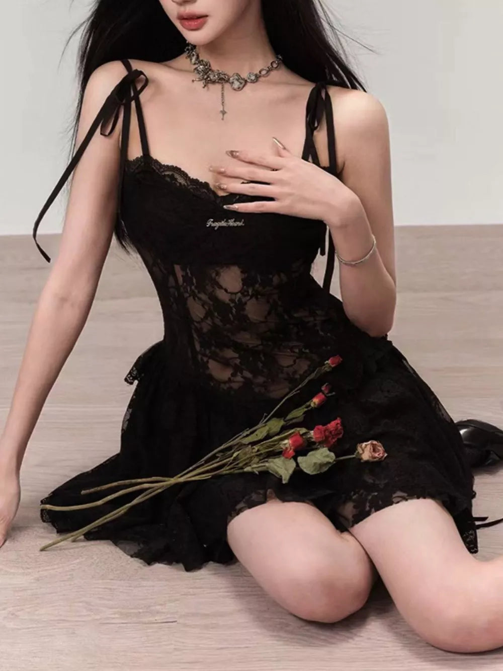 Black lace tie-shoulder mini dress with sheer bodice and ruffled hem.