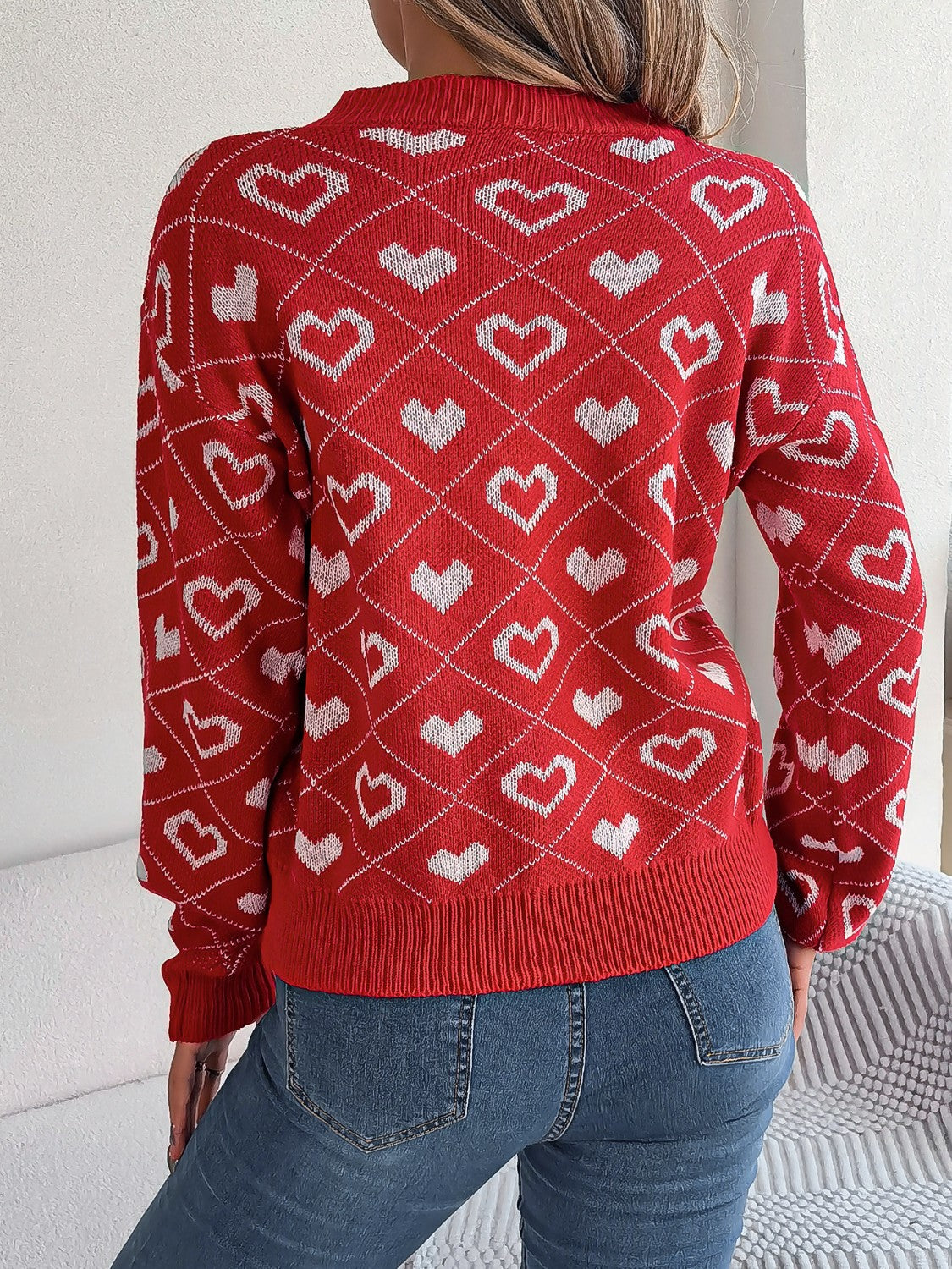 Deep Red acrylic V-neck sweater with allover white heart jacquard pattern and ribbed trim.