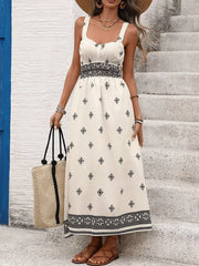 White midi dress with black geometric print, wide straps, smocked waist, and tiered hem.